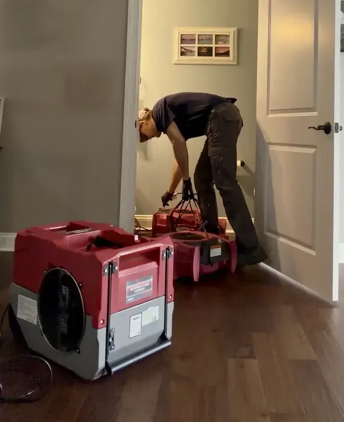 Technician beside drying equipment in a hallway