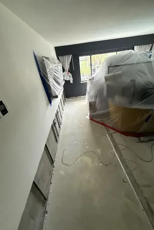 Plastic containment and a flood cut along a hallway wall during a dry-out