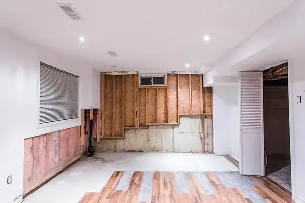 Finished basement room with wet drywall and insulation removed for drying