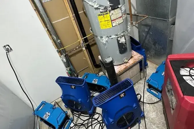 Air movers and a dehumidifier drying a water heater closet