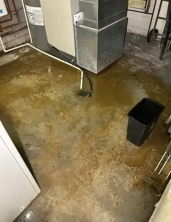 Sewage water covers a cellar floor beside a furnace.