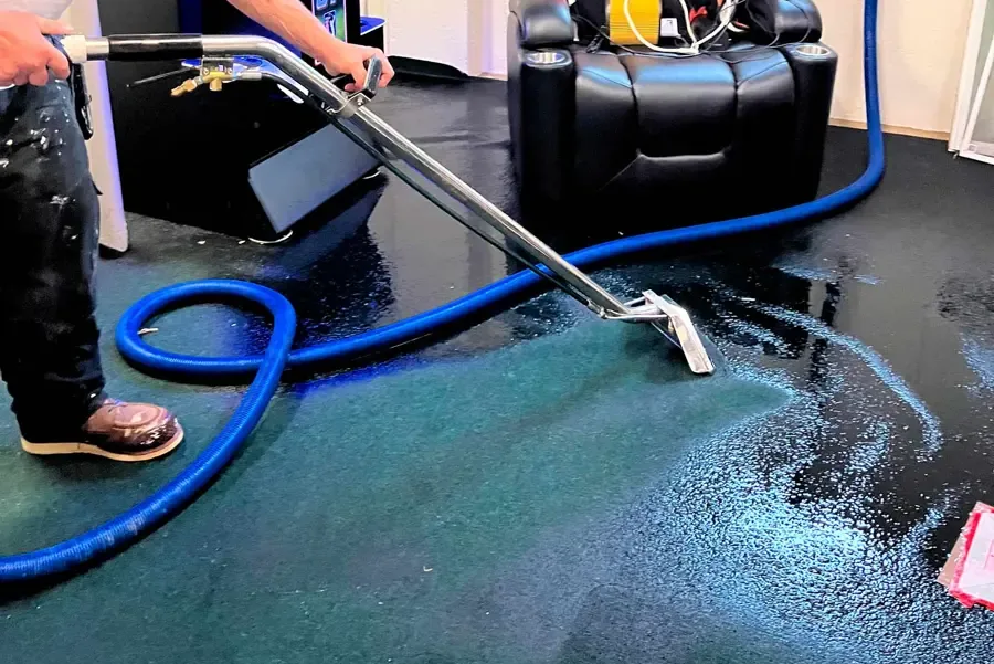 Extraction wand pulling water out of soaked carpet in a home theater room