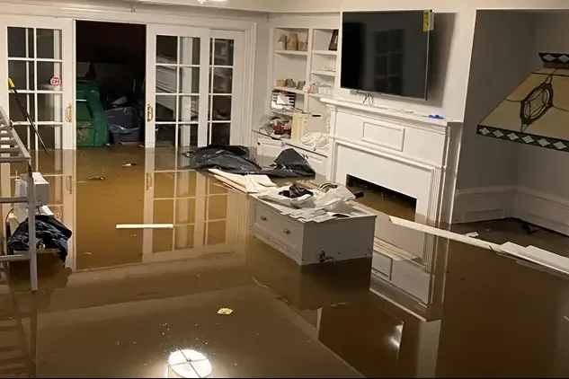 Storm water standing across the floor of a living room with built-in shelves and a fireplace