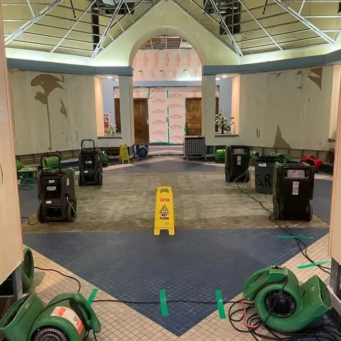 Multiple dehumidifiers and hoses arranged across a large interior room
