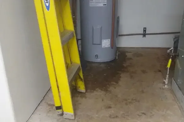 Water heater in a utility closet with leaked water spread across the floor